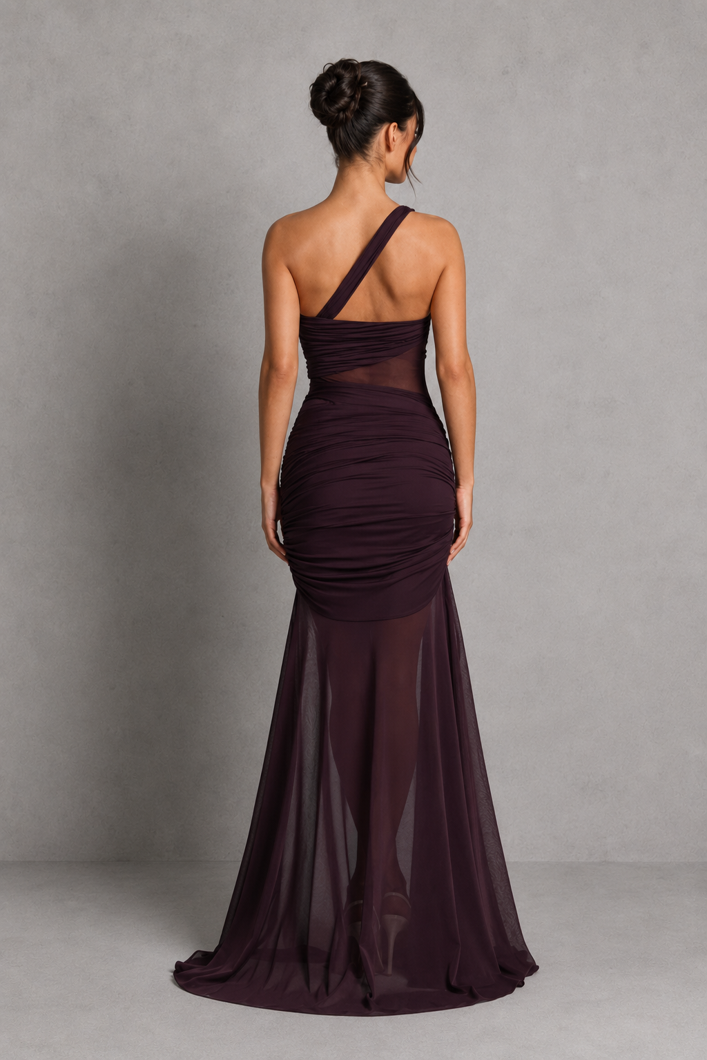 Woman wearing a dark purple one-shoulder gown against a gray background