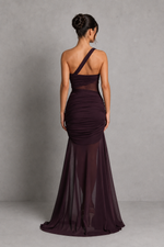 Woman wearing a dark purple one-shoulder gown against a gray background