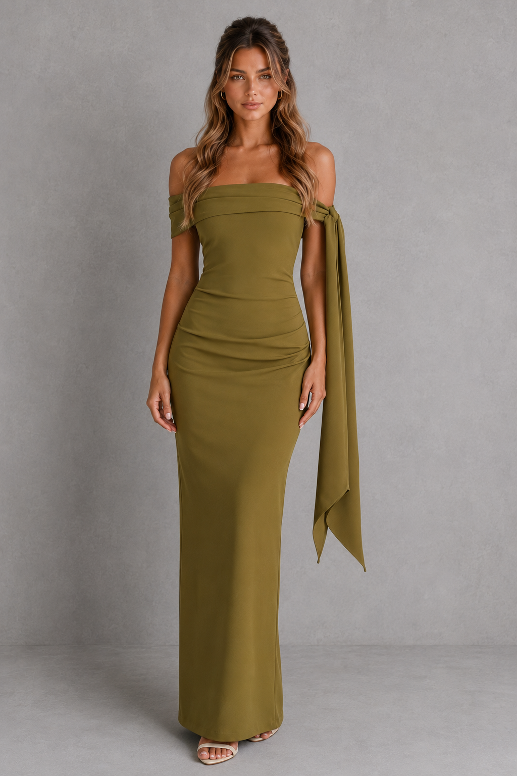 Woman wearing a green strapless dress with a draped design against a gray background