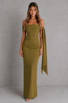 Woman wearing a green strapless dress with a draped design against a gray background