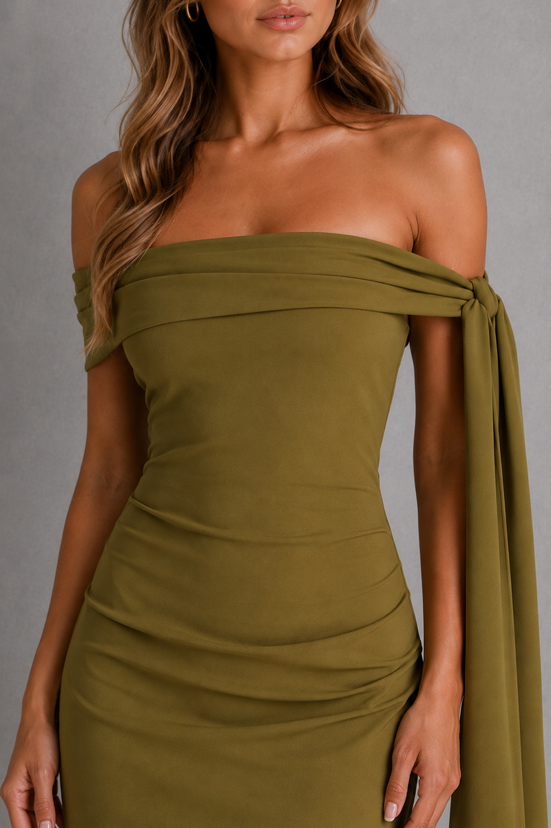 Woman wearing a green off-shoulder dress against a gray background