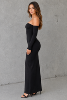 Woman wearing a black off-shoulder dress against a gray background