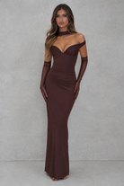Woman wearing a brown evening gown with mesh gloves against a gray background