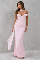 Woman wearing a pink off-shoulder gown against a gray background