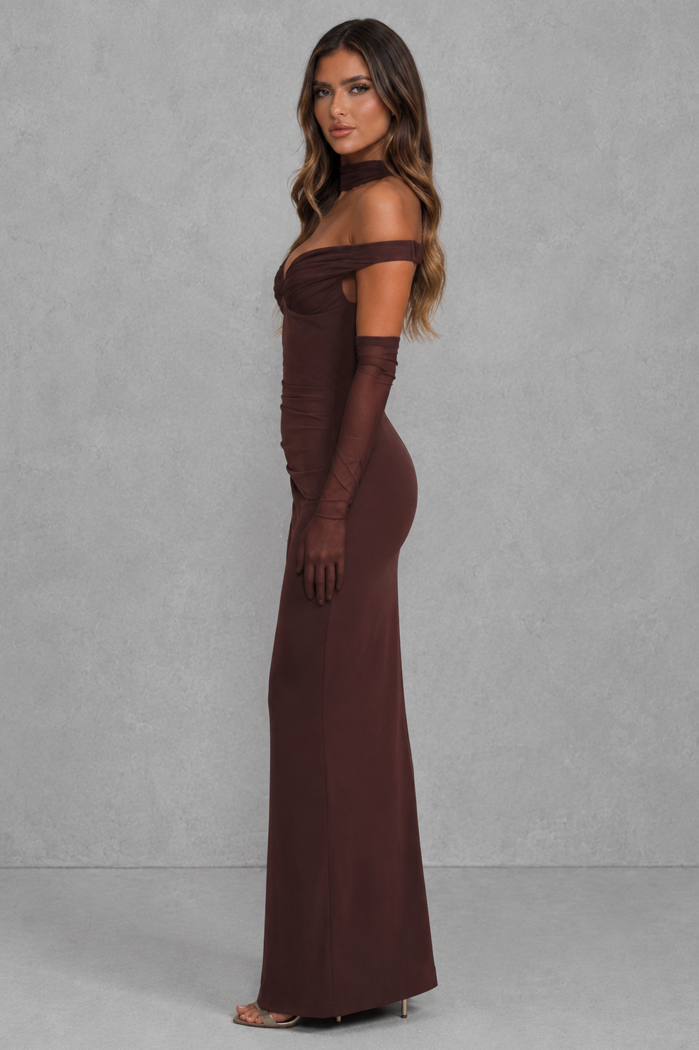 Woman wearing a brown evening gown against a gray background