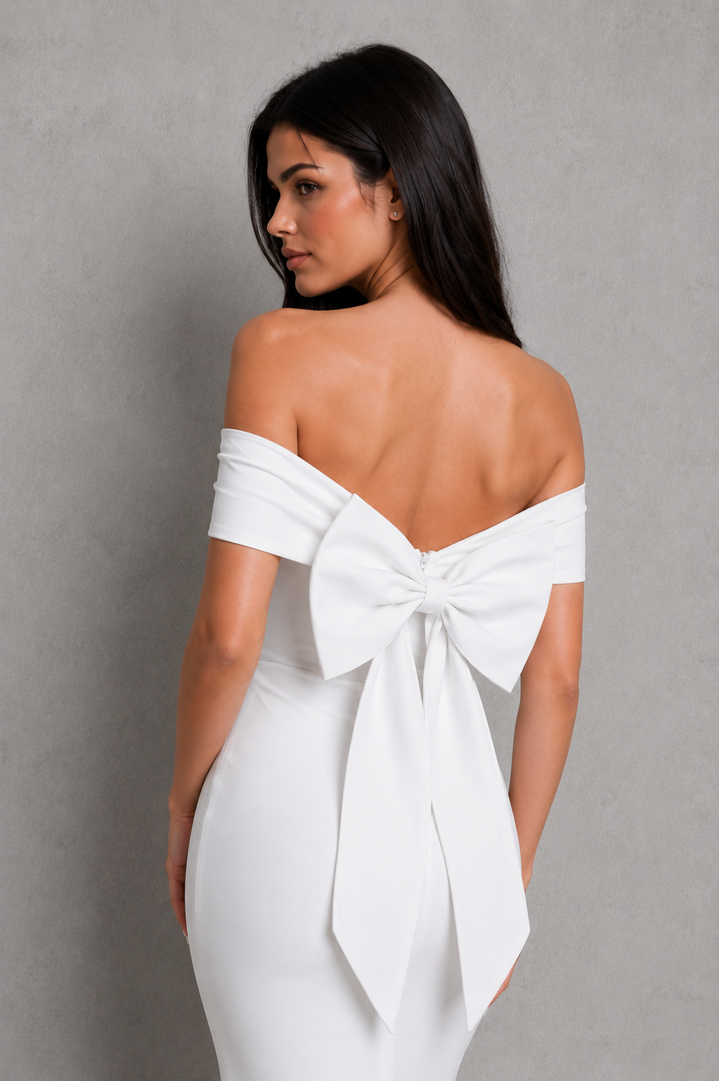 Woman wearing a white off-shoulder dress with a large bow detail on a gray background