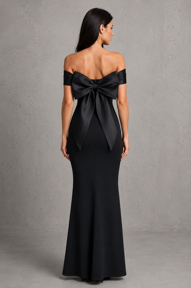 Woman wearing a black off-shoulder gown with a large bow detail on a gray background