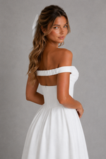Woman wearing a white off-shoulder dress against a gray background