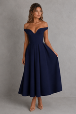 Woman wearing a navy off-shoulder dress against a gray background