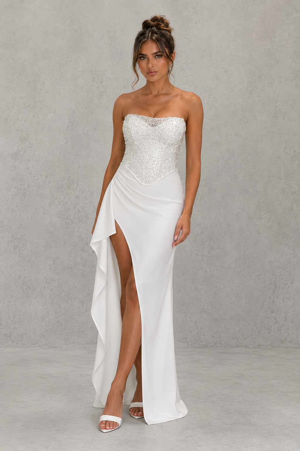 Woman wearing a strapless white gown with a high slit on a gray background