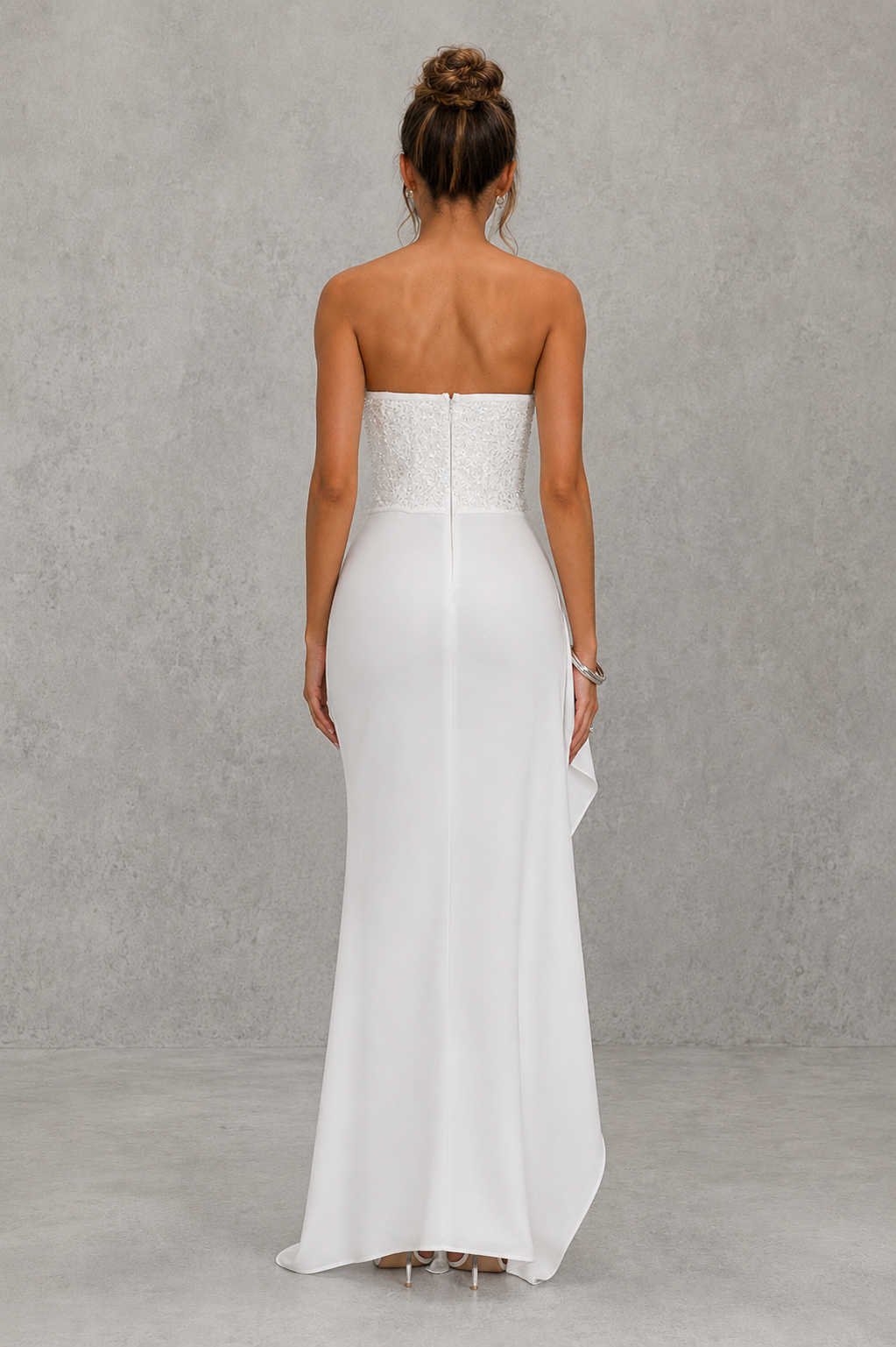 Woman wearing a strapless white gown against a gray background