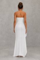 Woman wearing a strapless white gown against a gray background