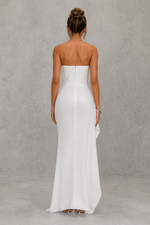 Woman wearing a strapless white gown against a gray background