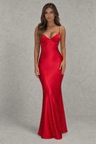Woman wearing a red satin evening gown against a gray background