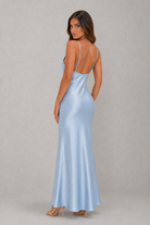 Woman wearing a light blue satin gown with a plain background