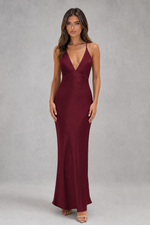 Woman wearing a burgundy evening gown against a gray background