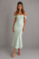 Woman wearing a light green off-shoulder dress against a gray background