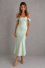 Woman wearing a light green off-shoulder dress against a gray background