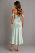 Woman wearing a light green off-shoulder dress against a gray background