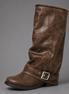 Women’s black slouchy knee-high boots with buckle strap, round toe, low block heel and chunky lug-tread sole.