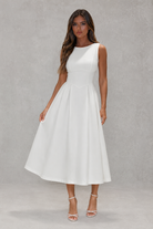 Woman wearing a white dress against a gray background
