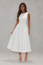 Woman wearing a white dress against a gray background