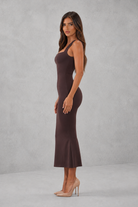 Woman wearing a brown dress against a gray background