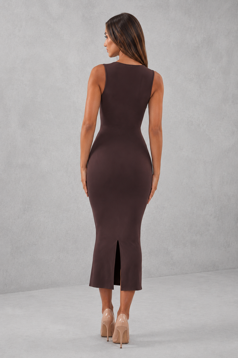 Woman wearing a brown sleeveless dress with a slit on a gray background