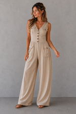Woman wearing a beige jumpsuit against a gray background