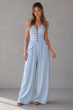 Woman wearing a light blue denim jumpsuit against a plain background