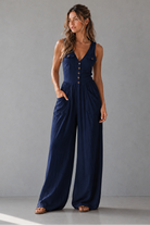 Woman wearing a navy blue jumpsuit against a gray background