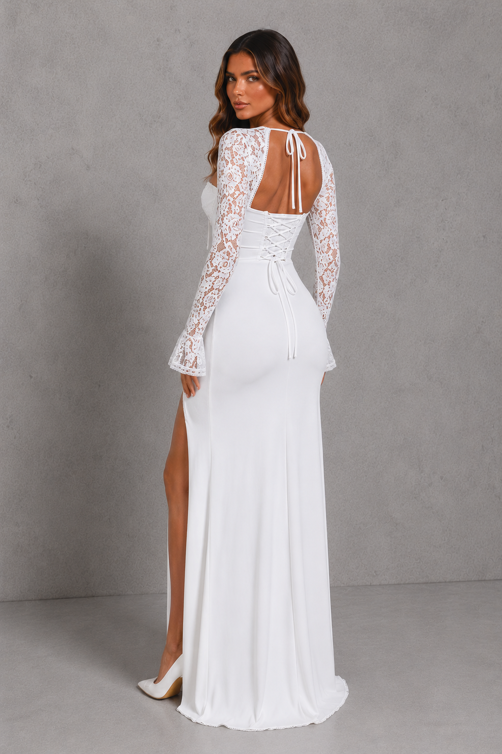 Woman wearing a white lace wedding dress with long sleeves against a gray background