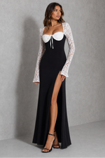 Woman wearing a black dress with a white lace overlay against a gray background