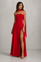 Woman wearing a red strapless gown with a slit on a gray background