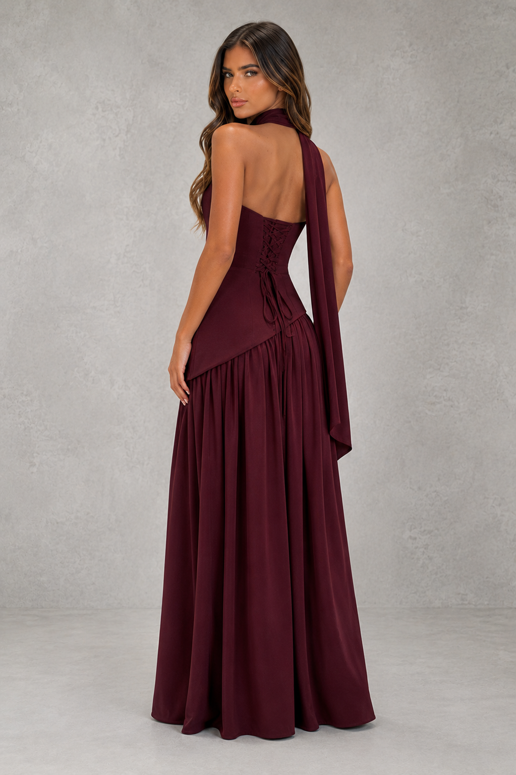Woman wearing a burgundy evening gown against a gray background