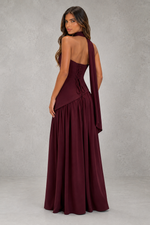 Woman wearing a burgundy evening gown against a gray background