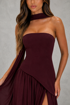 Burgundy strapless dress with a draped design on a gray background