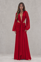 Woman wearing a red dress with long sleeves against a gray background