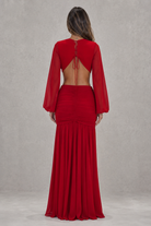 Red evening gown with long sleeves and open back on a plain background