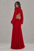 Red evening gown with sheer sleeves on a plain background