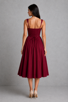 Woman wearing a burgundy dress against a gray background