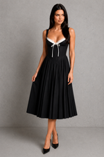 Woman wearing a black dress with white accents against a gray background