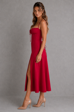 Woman wearing a red dress with a slit on a gray background