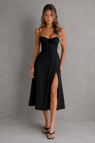 Woman wearing a black dress with a high slit on a gray background
