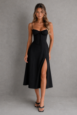Woman wearing a black dress with a high slit on a gray background