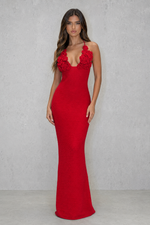 Woman wearing a red evening gown with floral details against a gray background
