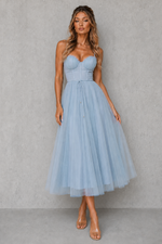 Woman wearing a light blue strapless dress against a gray background