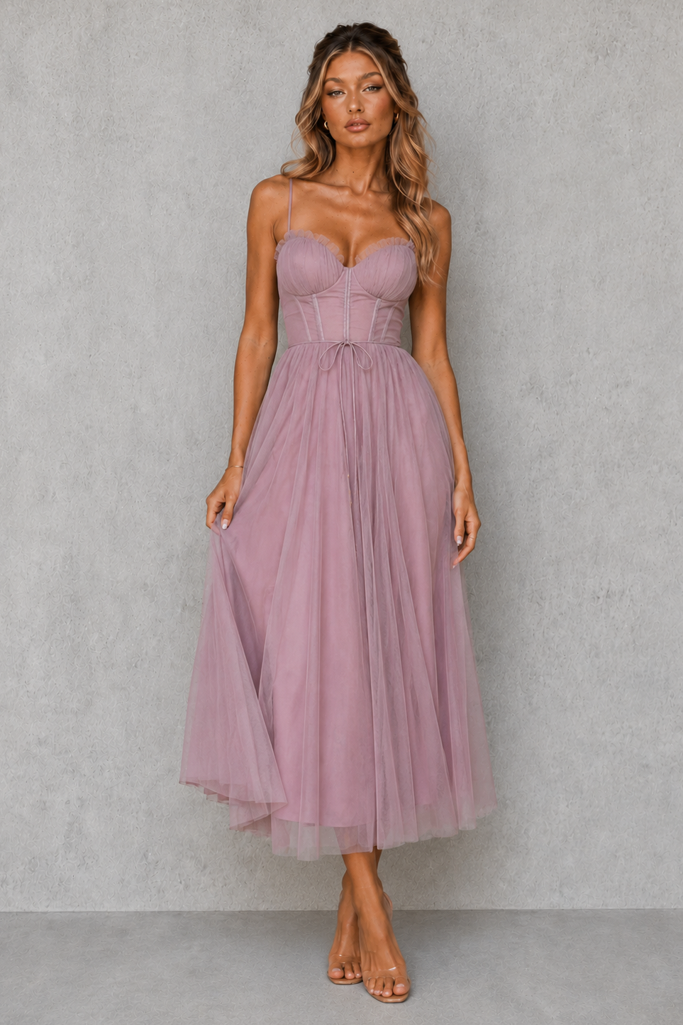 Woman wearing a strapless pink dress against a gray background