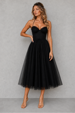 Woman wearing a black tulle dress against a gray background
