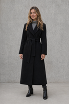 Women's elegant wrap coat in a longline design with a tailored lapel collar and adjustable matching waist belt, offering a flattering regular fit and lightweight warmth for autumn and winter wear.